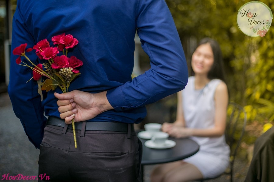 Man Is Hiding Flowers Behind Their Backs To His Girlfriend.